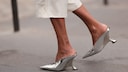 Frauenfüße mit Kitten Heels in Metallic-Silber