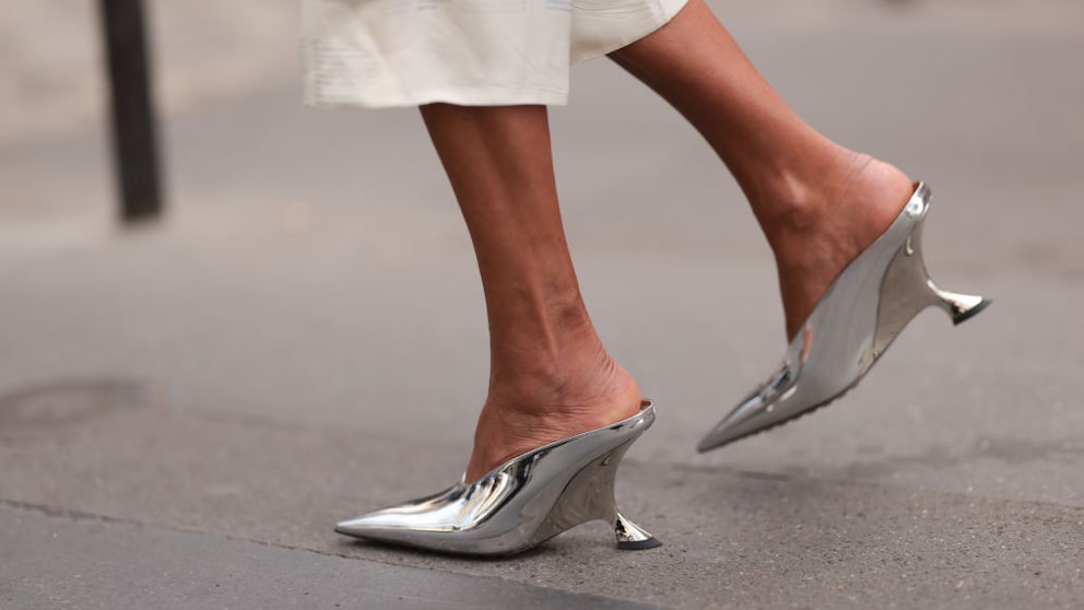 Frauenfüße mit Kitten Heels in Metallic-Silber