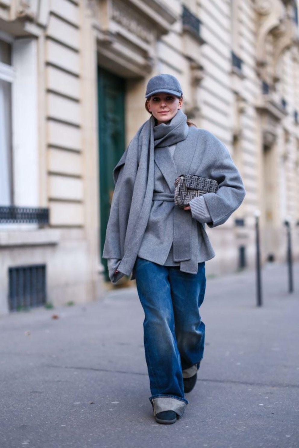 Frau mit grauem Mantel und blauer, leicht ausgewaschener Jeans auf der Straße