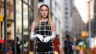 Frau in schwarz-weiß-kariertem Kleid und weißen Handschuhen