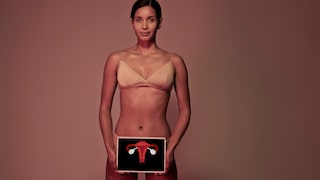 Frau in Unterwäsche, die ein medizinisches Schaubild vor ihren Genitalbereich hält