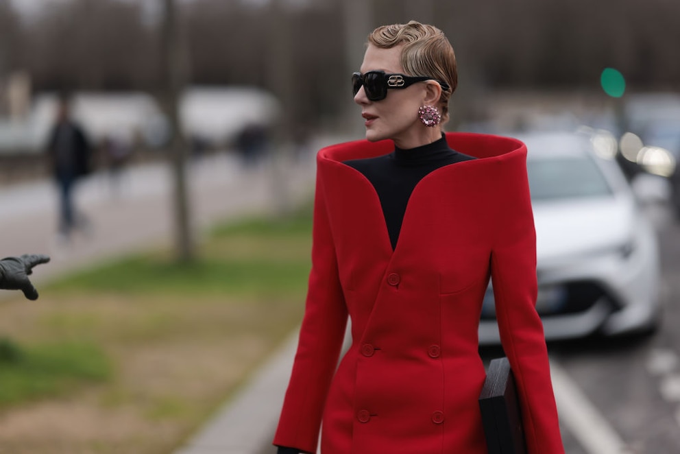 Streetstyle. Frau mit schwarzem Rollkragen und rotem Mantel von Balenciaga mit großen Ohrringen mit rosa Steinchen