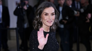 Letizia von Spanien winkt in die Kamera. Sie trägt ein schwarzes Kleid und rötlichen Lidschatten mit Kupfer