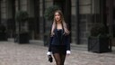 Frau mit schwarzem Bandeau-Minikleid, Blazer, Strumpfhose, Clutch und Boots. Streetstyle