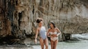 Zwei Frauen in Badeanzug und Bikini im Meer, die sich anlachen und Spaß haben. Ein tolles Shooting, sehr authentisch und schön ohne perfekt zu sein. So wie der Sommer sein sollte