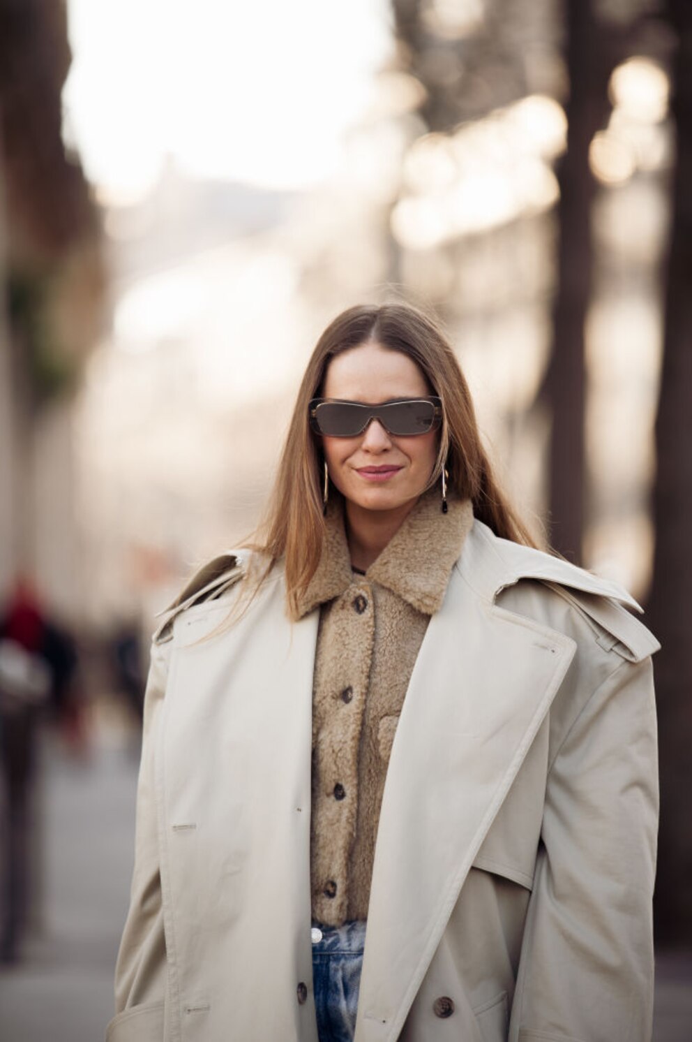 Streetstyle einer Frau mit Long Bob, Sonnenbrille und dunkelbeigem Plüsch-Shirt mit Trenchcoat darüber