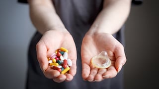 Concept of safe sex and treatment of venereal diseases. Girl holds condom and pills in palms