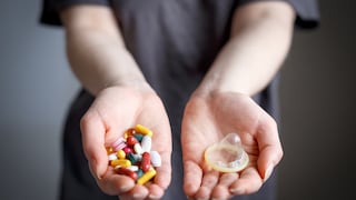 Concept of safe sex and treatment of venereal diseases. Girl holds condom and pills in palms