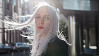 Junge Frau mit siber-grauem Haar, das im Wind weht