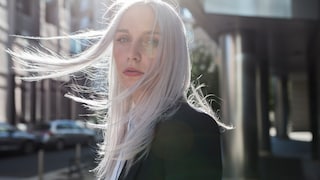 Junge Frau mit siber-grauem Haar, das im Wind weht
