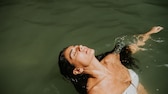 Frau mit langen dunklen Haaren beim Schwimmen