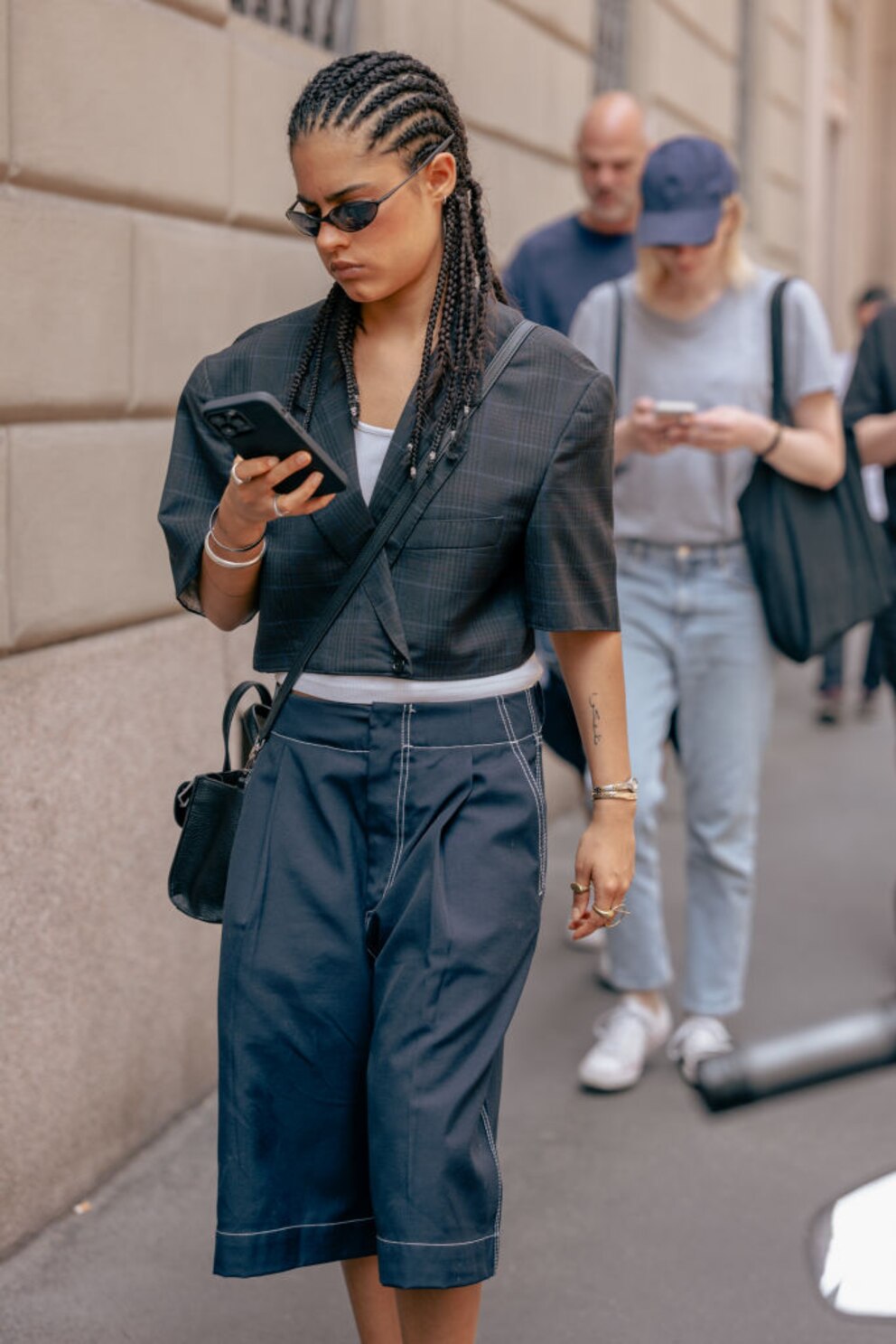 Streetstyle. Frau am Handy mit Bermudas und kurzem Blazer in dunklem Jeanston