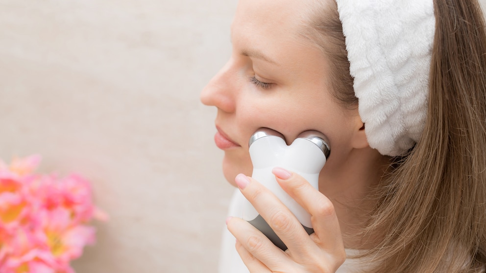 Frau im Bad mit Massagegerät im Gesicht