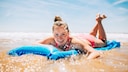 Frau mit Dutt auf Luftmatratze im Meer