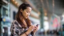 Frau mit Handy am Bahnhof