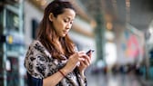 Frau mit Handy am Bahnhof