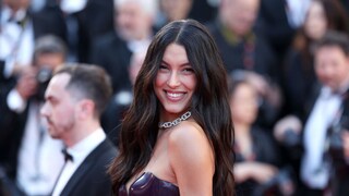 Rebecca Mir mit schwarzem Latex-Kleid auf dem roten Teppich in Cannes. Sie lacht strahlend in die Kamera