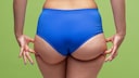 Frau im blauen Slip kneift sich in die Po-Seiten, die noch keine Reiterhosen sind, aber ein anderes Foto davon zu finden, ist beinahe unmöglich