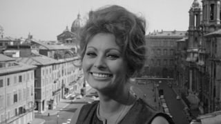 Sophia Loren lächelt sehr süß in die Kamera. Hinter ihr eine italienische Stadtkulisse