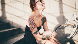 Frau auf Stufen mit Tattoos. Sie sieht typisch Berlin aus, aber herzlich besser gelaunt ;)
