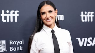 Demi Moore lachend in weißer Bluse und schwarzer Krawatte auf dem roten Teppich