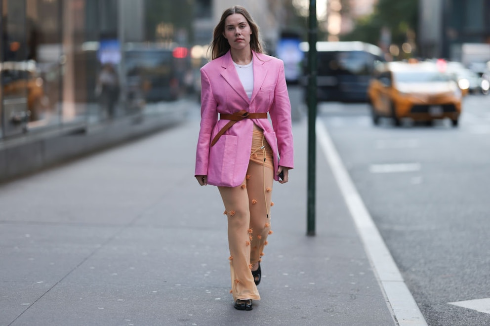 Streetstyle. Frau im pinken Blazer mit Taillengürtel und durchsichtiger Hose