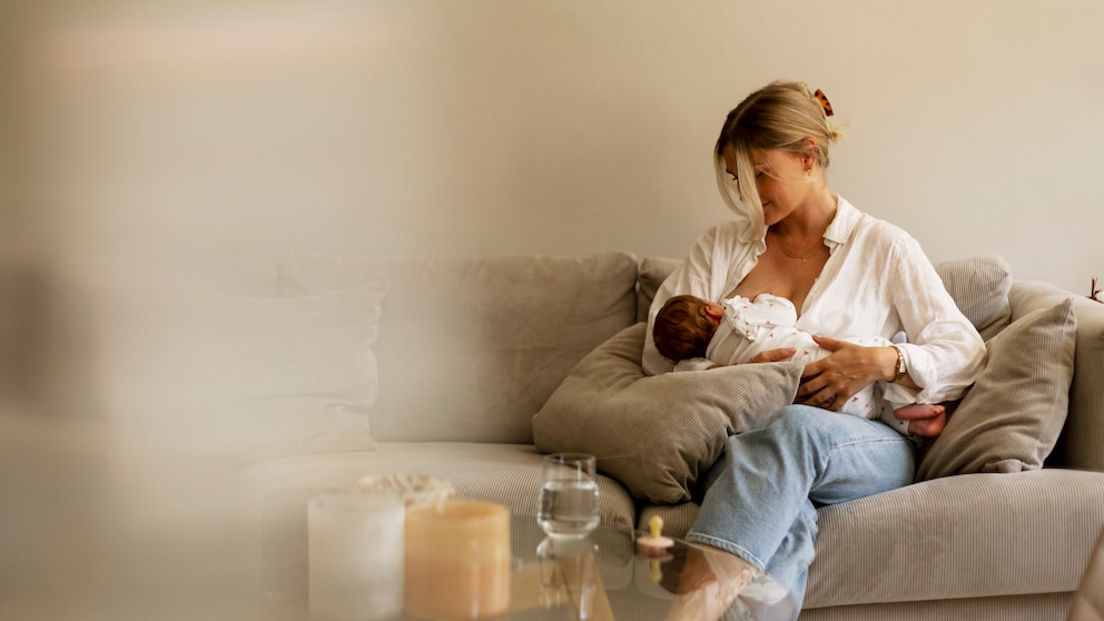 Frau stillt Baby auf Sofa