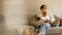 Frau stillt Baby auf Sofa