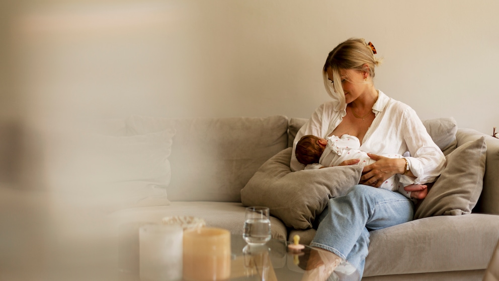 Frau stillt Baby auf Sofa