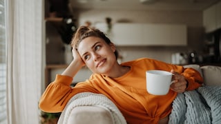 Frau auf dem Sofa mit Tee, wirkt entspannt und happy, very Honjok