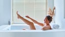 Frau rasiert sich die Beine in der Wanne