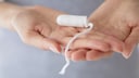 Frauenhände halten Tampon, der ein probiotischer Tampon sein könnte