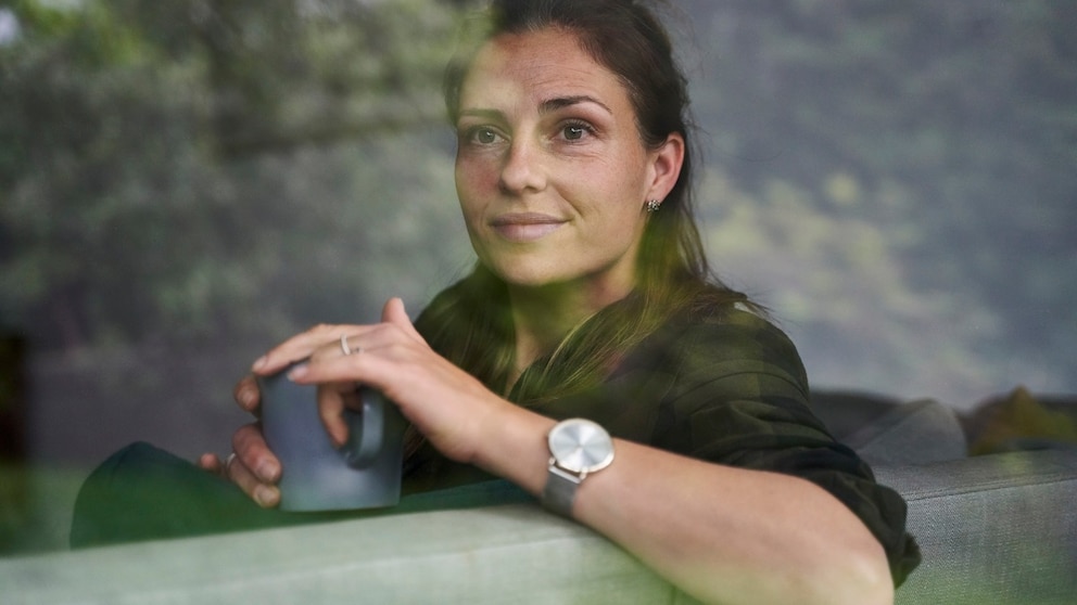 Frau mit Tasse Tee auf dem Sofa. Hilft bestimmt in den Wechseljahren. Und auch so. Eine Tasse Tee tut immer gut, oder?