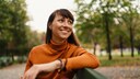 Frau sitzt glücklich lachend auf Bank, bestimmt hat sie Thymian gegen Menstruationsbeschwerden genommen
