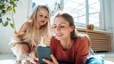 Mutter und Tochter scrollen durchs Handy