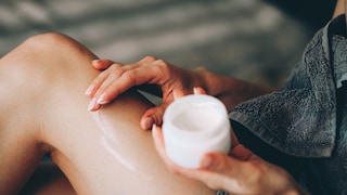 Frau cremt sich wahrscheinlich mit Bodylotion ein