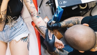 Frau wird mit Tattoos wird tätowiert