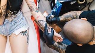 Frau wird mit Tattoos wird tätowiert