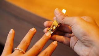 Frau schneidet Nägel mit Nagelnipser