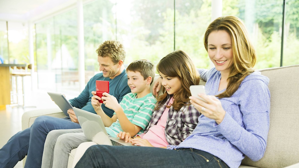 Familie sitzt auf dem Sofa und jeder ein Handy in der Hand