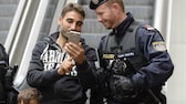 Mann und Polizist schauen auf ein Smartphone