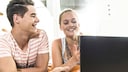 Junge und Mädchen lachen vor einem Laptop
