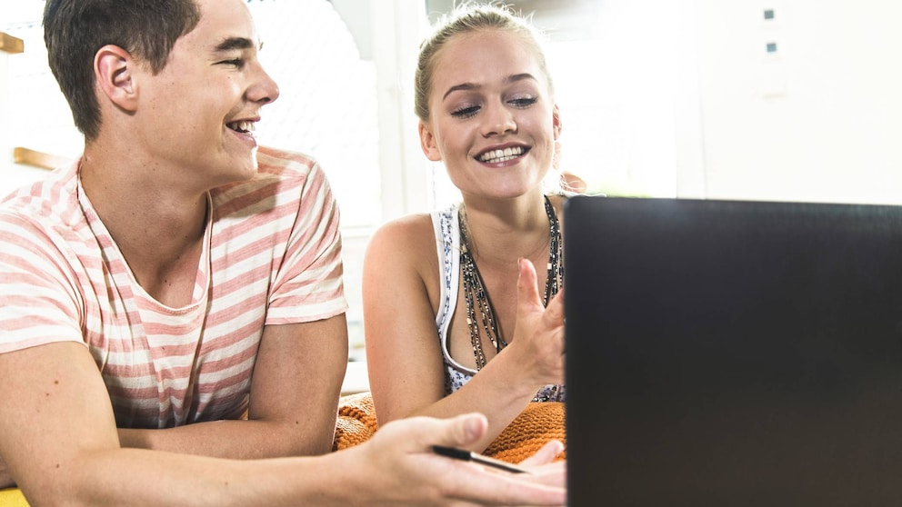 Junge und Mädchen lachen vor einem Laptop