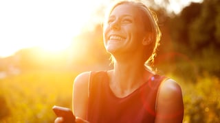 Sonne scheint auf Frau mit Smartphone