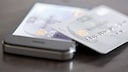 Ein Smartphone und eine Kreditkarte liegen auf einem Tisch