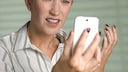 Frau schaut wütend auf ein Smartphone