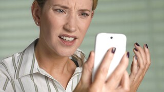 Frau schaut wütend auf ein Smartphone