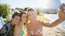 Drei Frauen am Strand machen ein Foto mit dem Smartphone von sich.