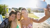 Drei Frauen am Strand machen ein Foto mit dem Smartphone von sich.