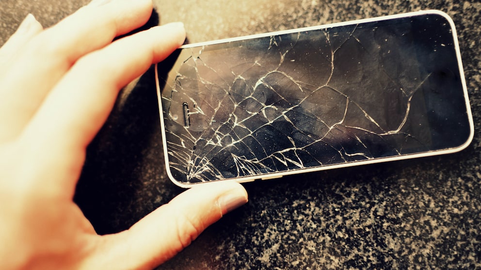 Hand hält ein kaputtes Smartphone-Display